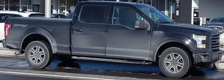 Sample CarGo still: a black Ford F-150 in profile in front of a storefront, driver and lettering blurred